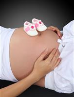Baby Shoes on Pregnant Woman stock photo