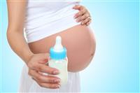 Pregnant Woman Holding Baby Bottle stock photo