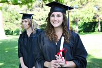 Pretty young woman at graduation holding diploma stock photo
