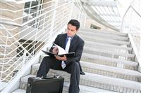 Business Man on Stairs Reviewing Notes stock photo