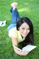 Young woman reading book in park stock photo