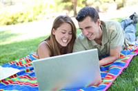 Couple on Laptop in Park stock photo