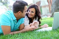 Attractive Couple on Grass with Computer stock photo